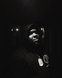 a black man in a hoodie standing in a dark room